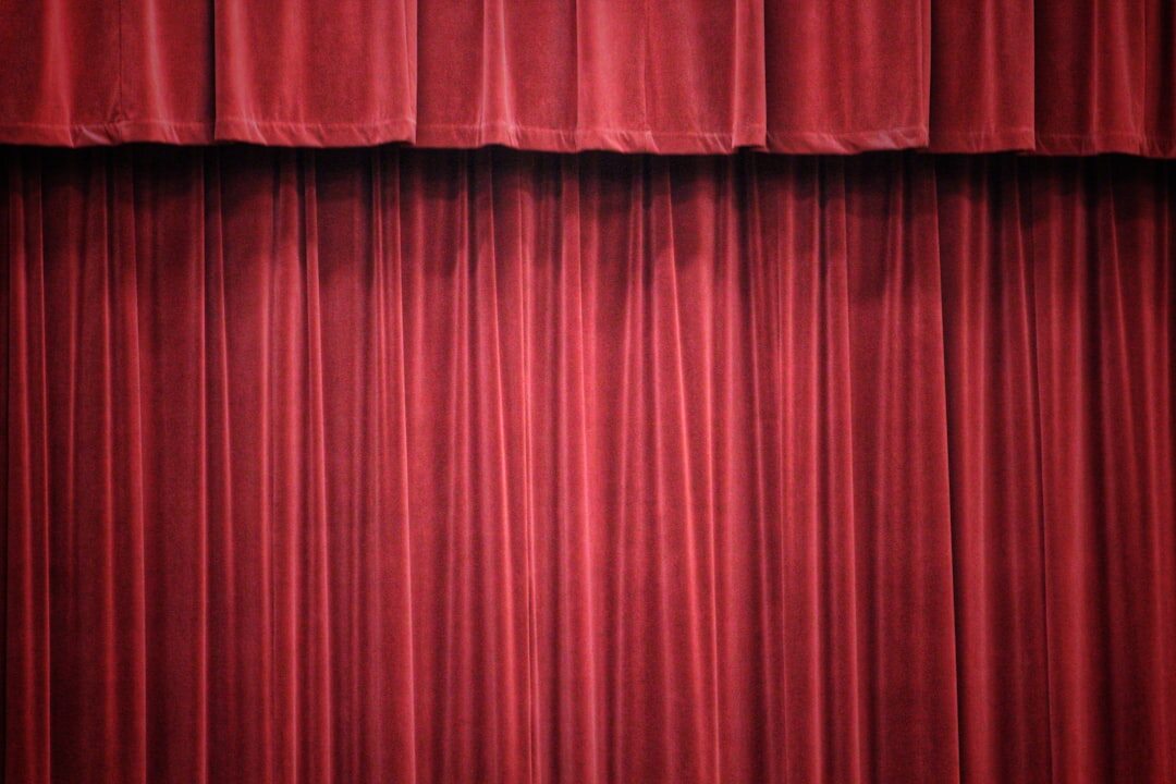 Empty theatre stage with red curtains and dramatic lighting
